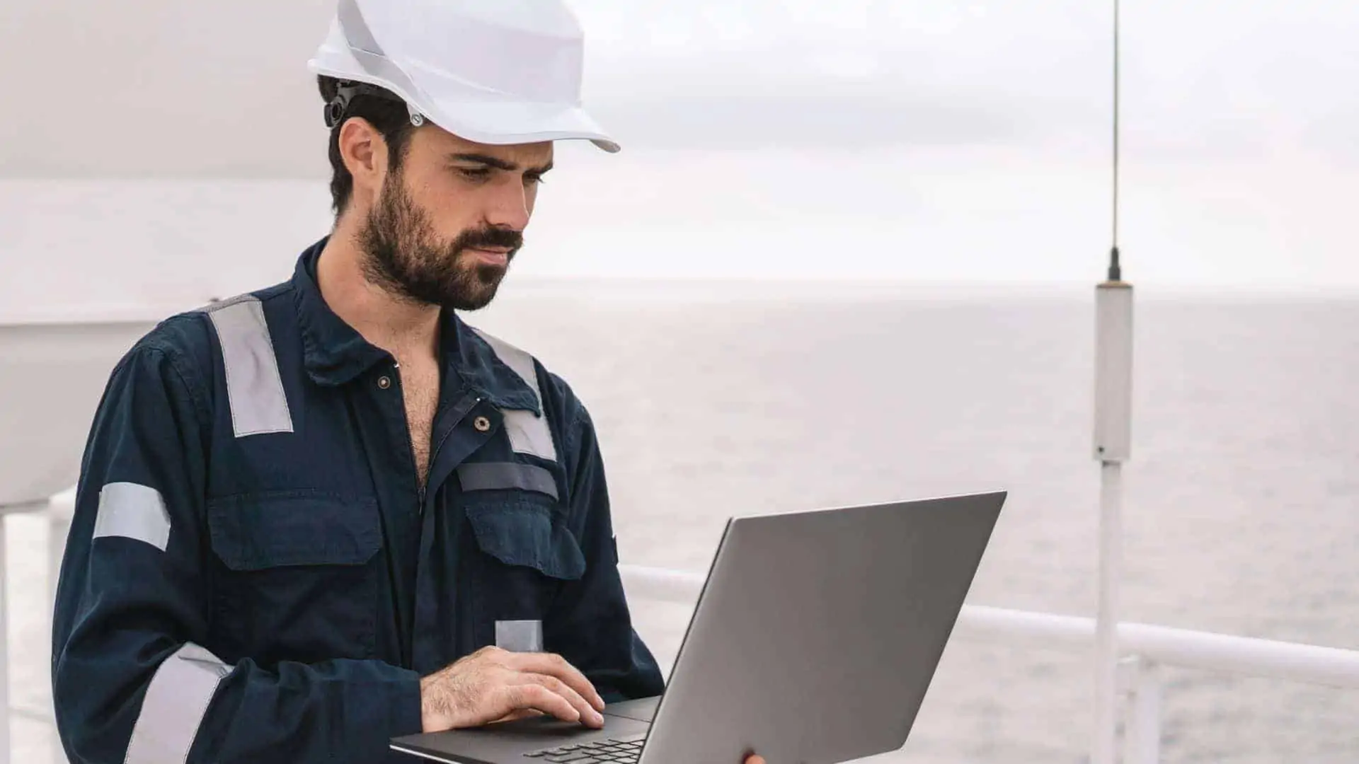 Marine engineer using laptop onboard vessel to access fleet management system.